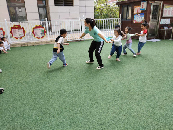 大班幼儿在老师的带领下玩老鹰捉小鸡游戏