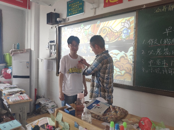 登封外国语高中时满飞老师为学生贴加油贴，带领学生考前宣誓.jpg